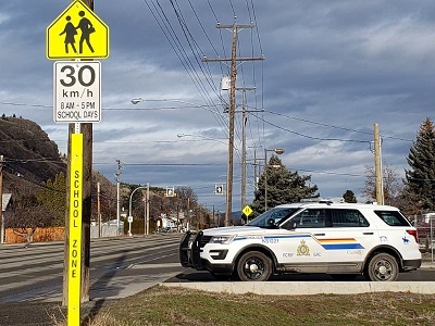 A police cruiser parked near a school speed zone sign