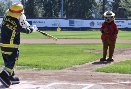 The Kamloops Fire Rescue mascot ‘Sparky’, (a dalmatian in a firefighter’s uniform), takes a swing at a softball pitched by the Kamloops RCMP mascot, Sgt Safety Bear (a bear in a Mountie Serge and hat). 