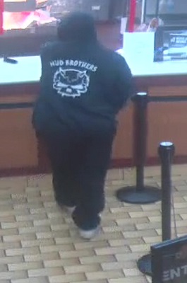 Caucasian female wearing black track pants, a black hoodie with <q>Mud Brothers</q> logo, white runners.