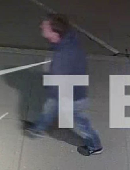 Suspect à l’extérieur : un homme de race blanche portant un jean bleu et un chandail à capuchon bleu foncé marchant à l’extérieur. Le capuchon est baissé. 