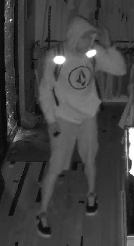 Suspect en short : Image de sécurité par vision nocturne d’un suspect vêtu d’un chandail, d’un short et portant un sac à dos. Le chandail comporte un logo à l’intérieur d’un cercle.
