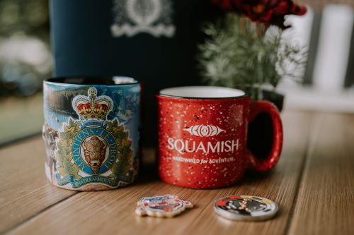 Two coffee mugs with RCMP and Squamish logos